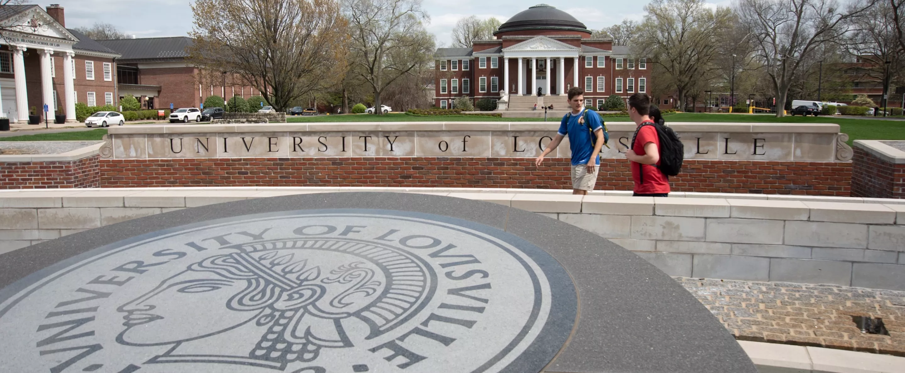 Three students walking past the 3rd Street entrance with Grawemeyer Hall and the School of Law in the background.