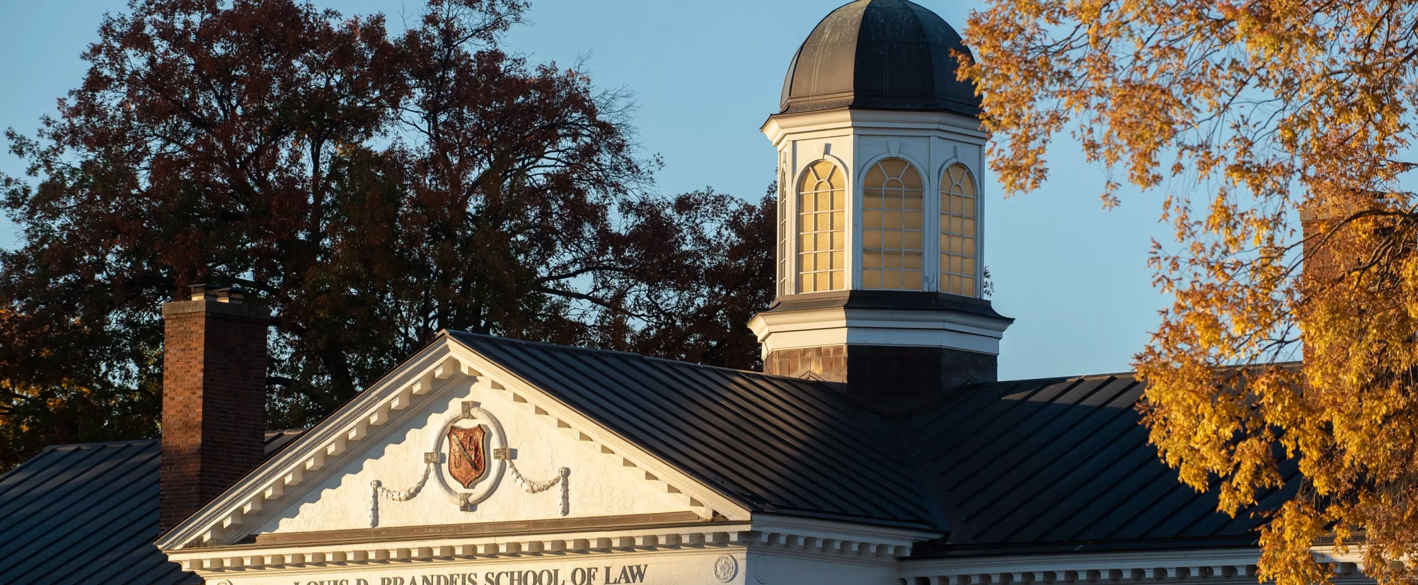 Top of the Louis Brandeis School of Law building against the sky on a fall day.