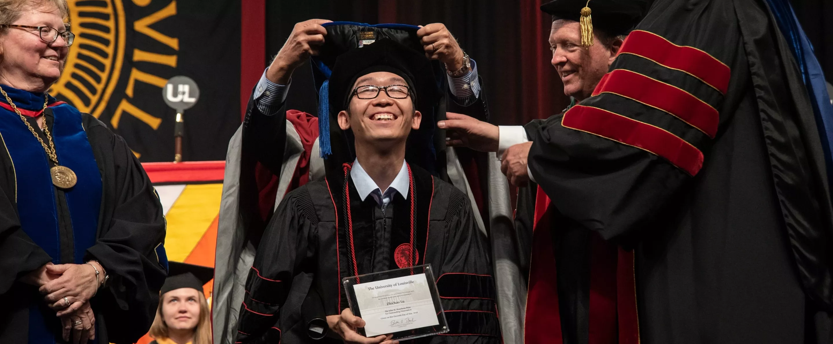 PHD student smiles at the Hooding Ceremony