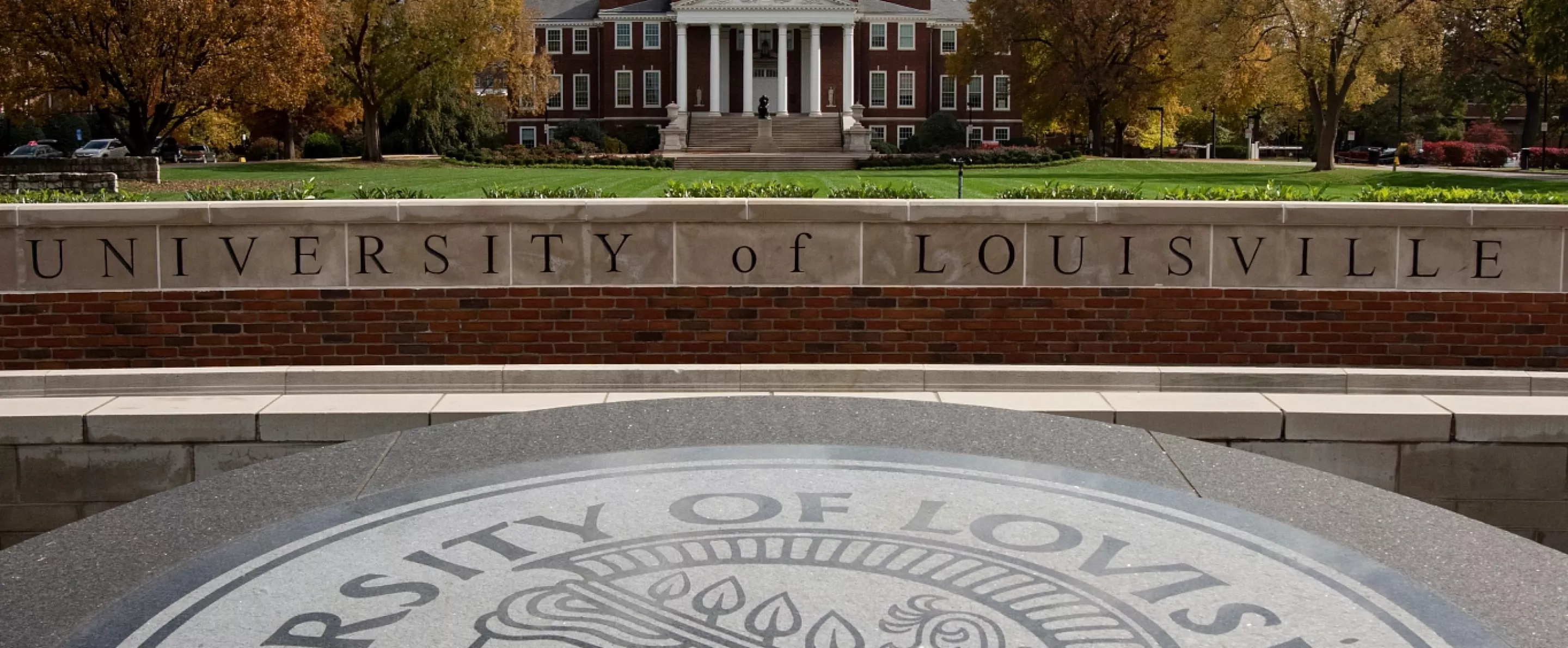 Wide-angle portrait of the exterior of Grawemeyer Hall and the Oval with the 3rd Street entrance sign and Minerva in the…