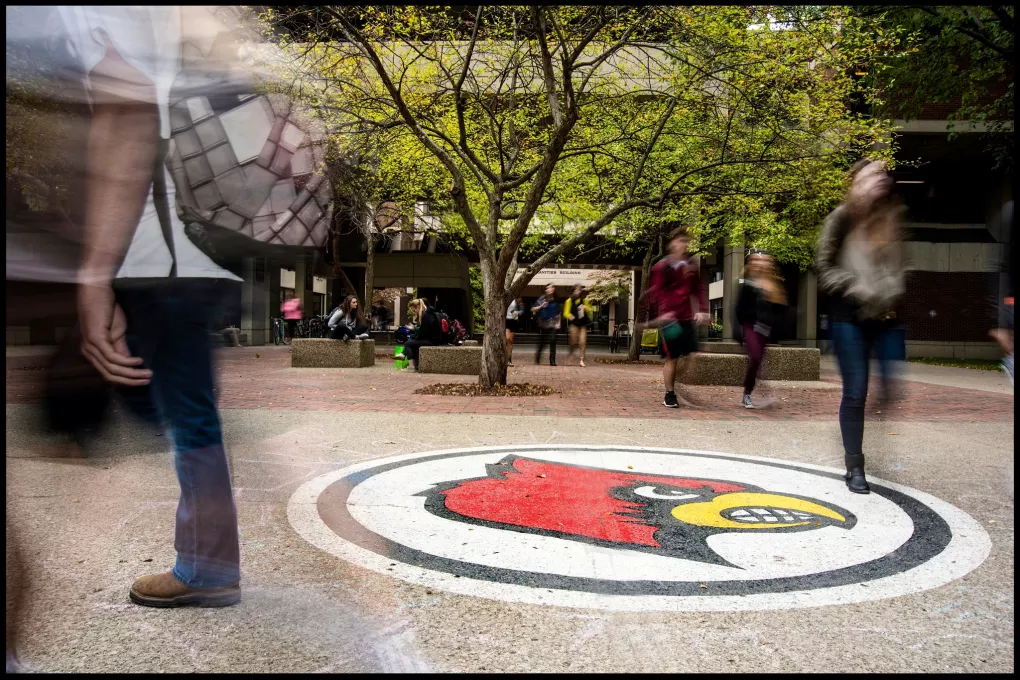 Blur of students walking by Cardinal Bird in front of Humanities