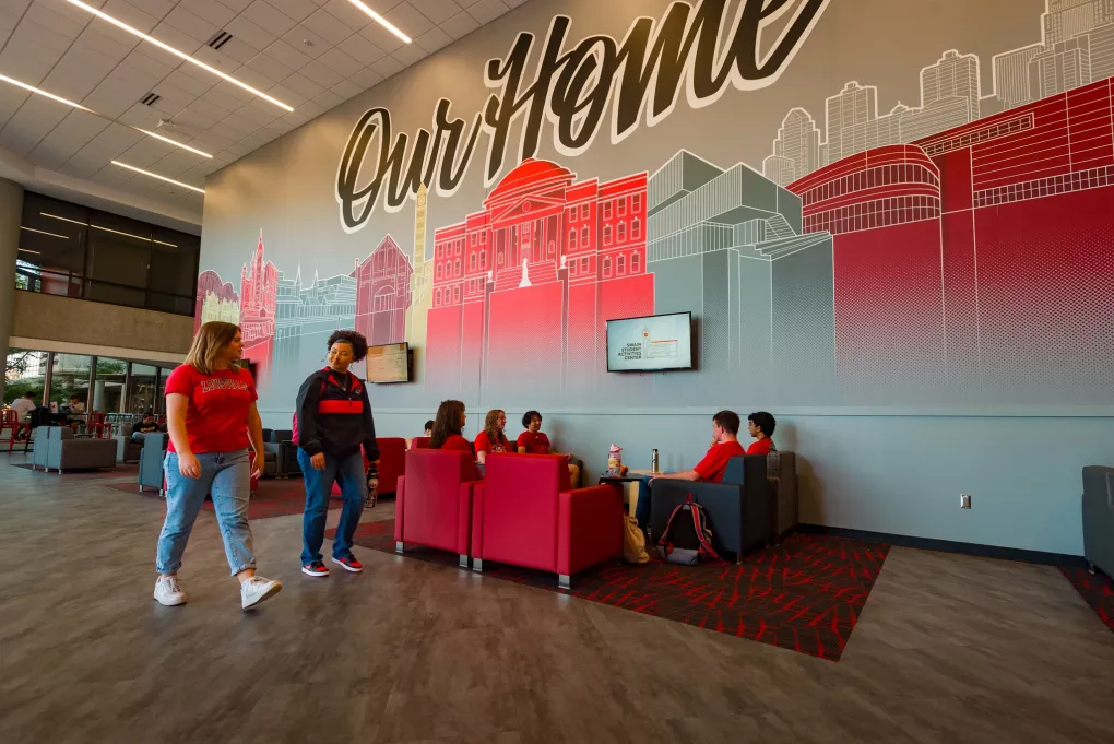 Two students in the foreground walking past other students in the SAC lounge