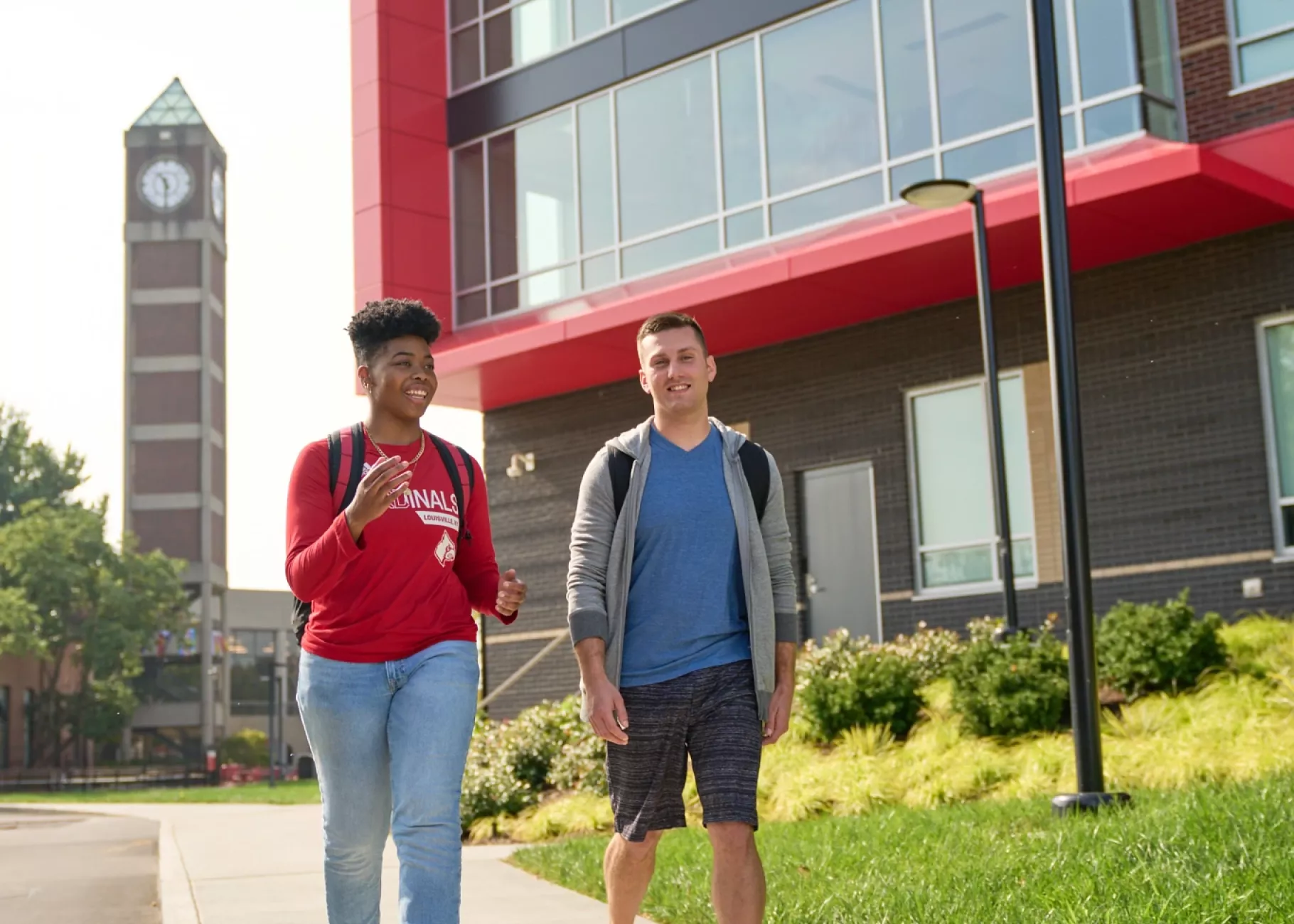 Two students walking by Belknap Residence Hall with the clock tower in the background.