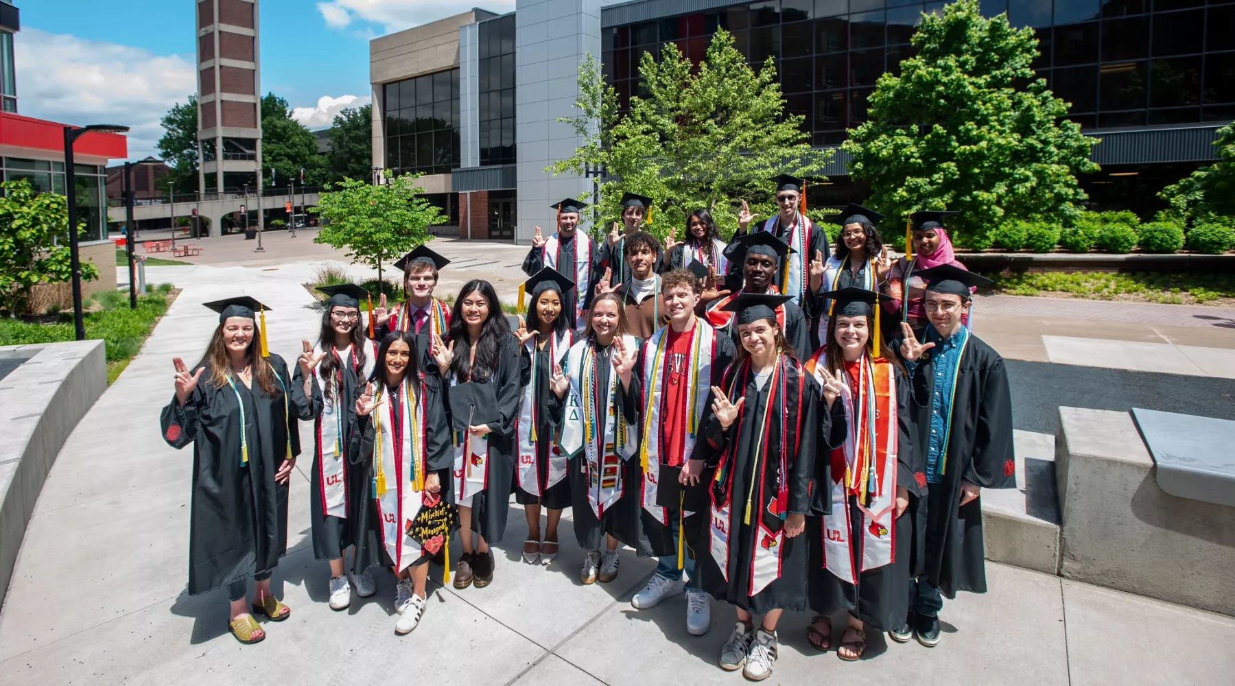 CEI Graduates posing in front of the SAC Clock Tower in robes