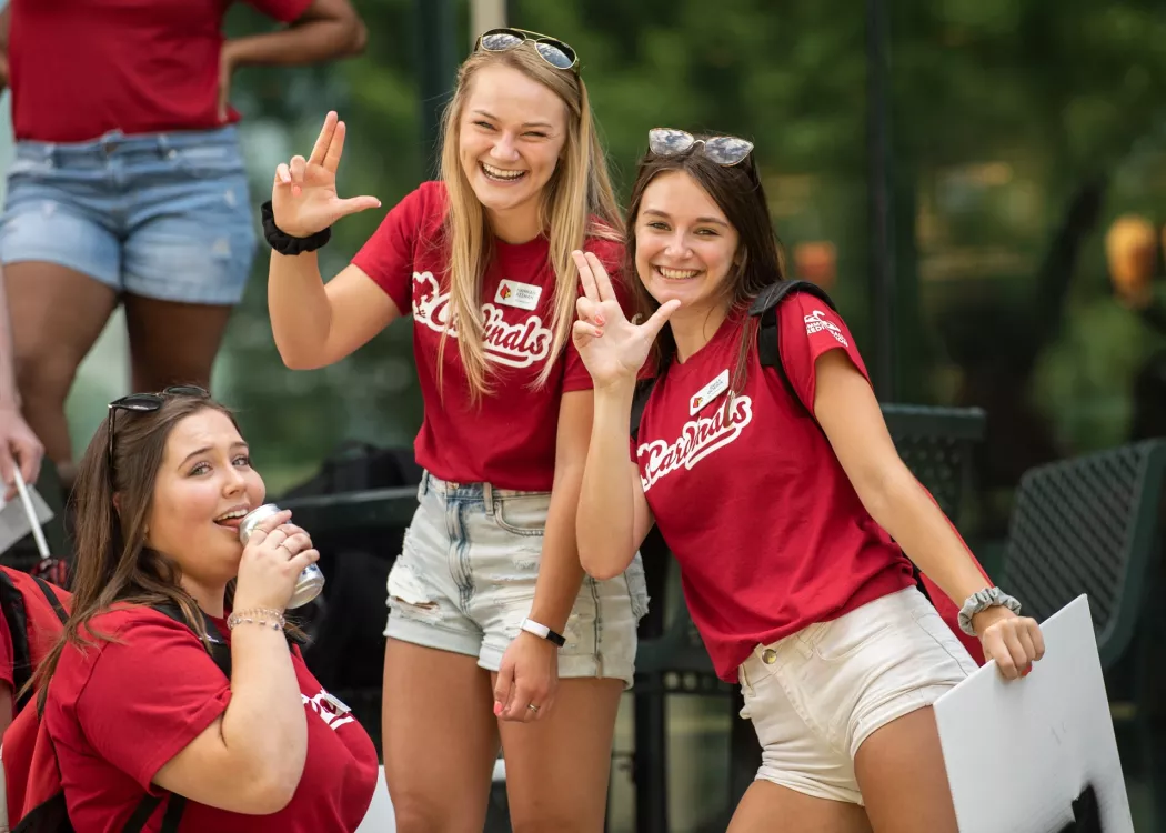 Three students at welcome week showing their spirit by putting up the L's