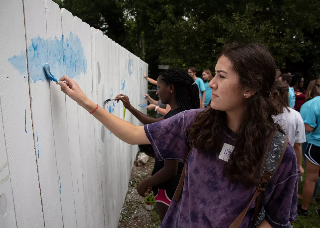 Students with SOUL work together to paint a fence