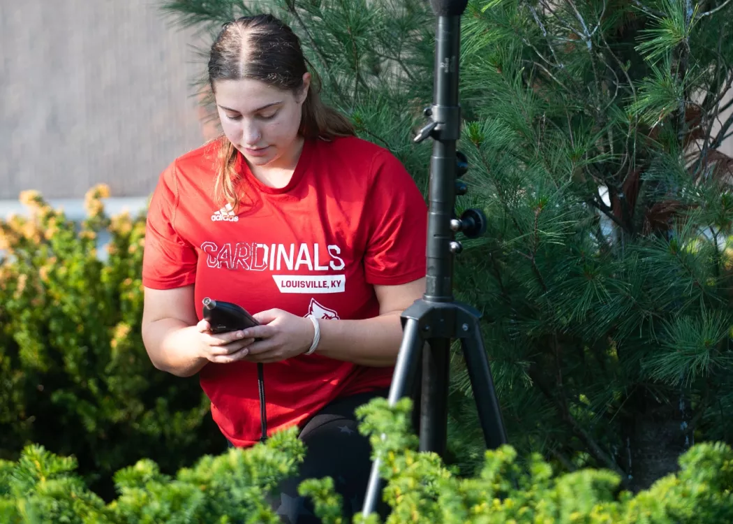 Madison Cicha sets up microphone during sound study summer research project with the Envirome