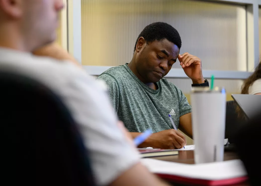Graduate student listening in a public health seminar and writing notes