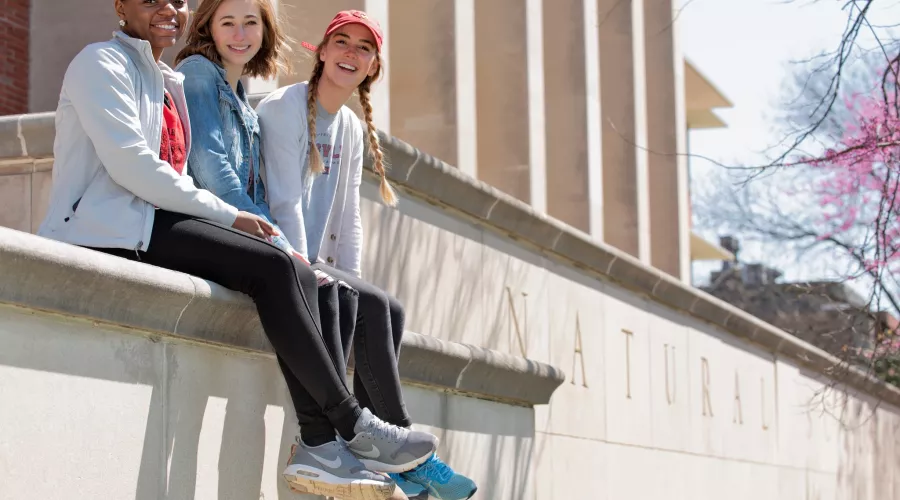 Three female students pose for a photo outside the Natural Sciences Building