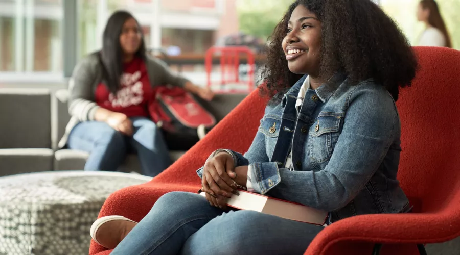 Student, Idaya Gager, sits in a red chair as she poses for campaign.