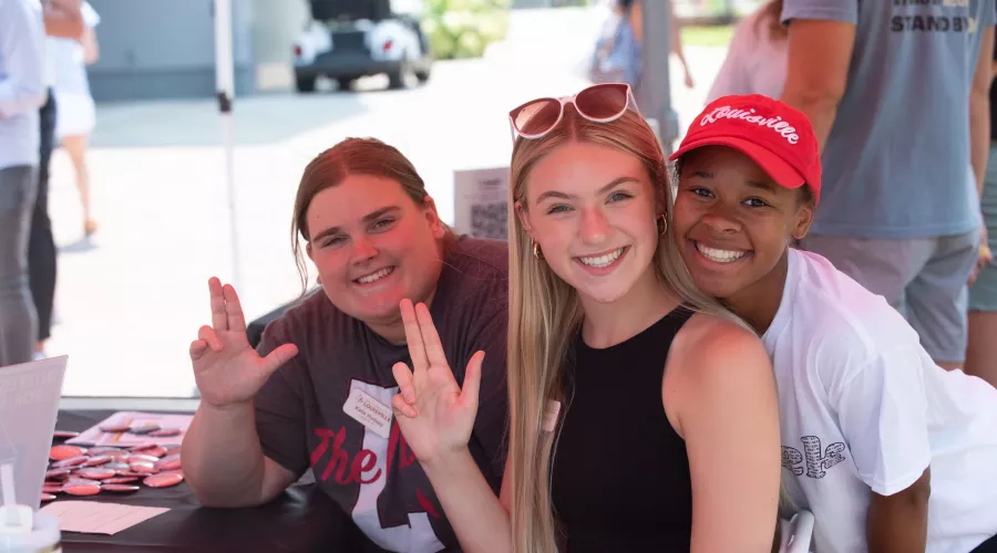 Three students smiling at the camera during Homecoming