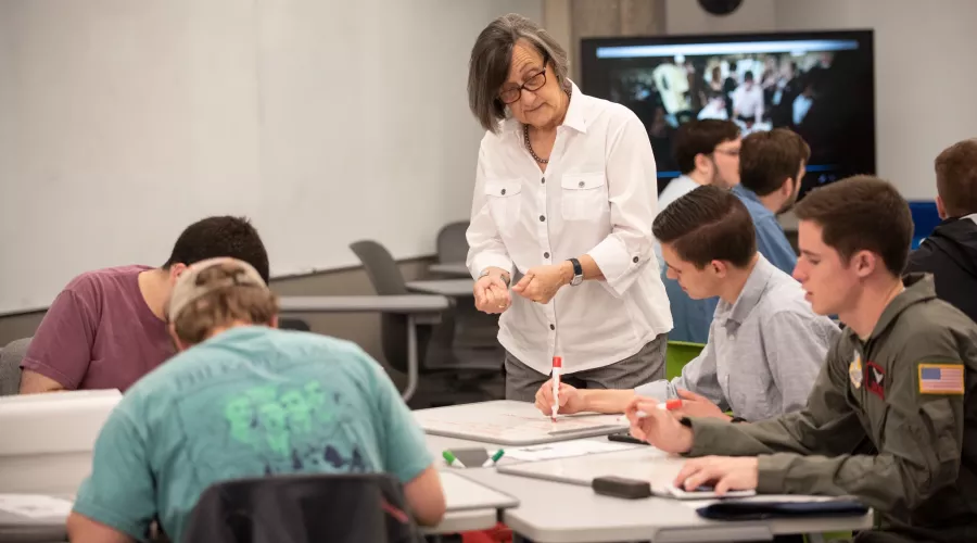 Professor helps students solve problems on their white boards