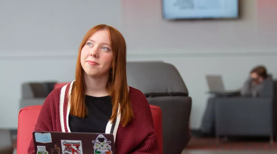 A student pauses in thought while working on a laptop in the Belknap Academic Building