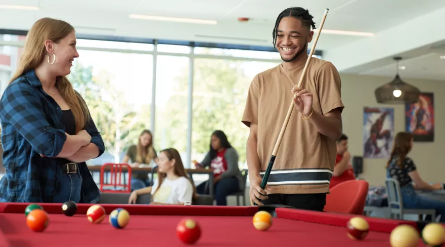 Two students playing pool in the Belknap Residence Hall.