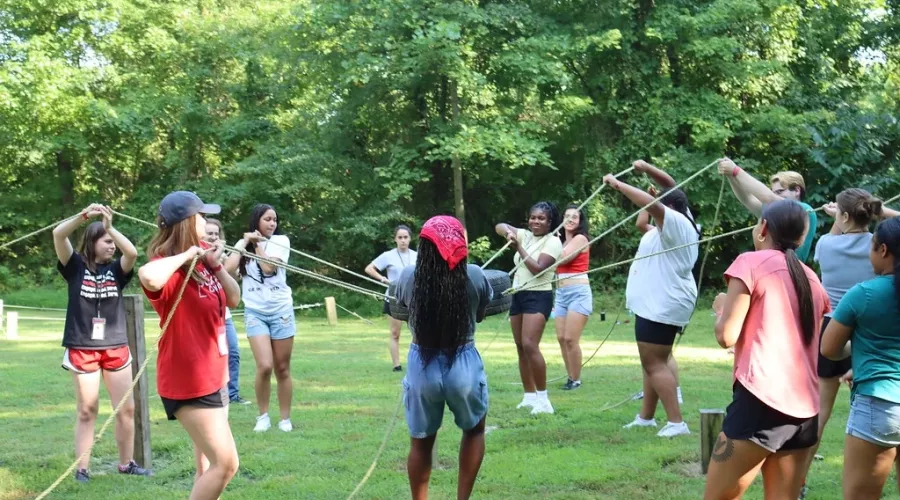 Trailblazers working together to lift a tire with ropes