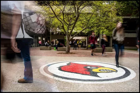 Blur of students walking by Cardinal Bird in front of Humanities