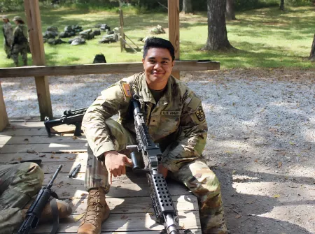 Image of an ROTC cadet posing with a firearm